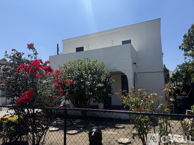 A white building with a perforated fence in front.