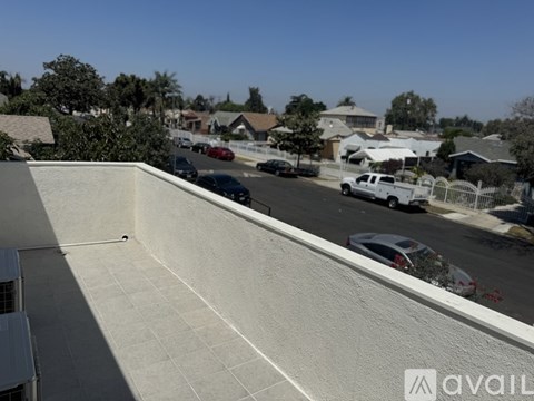 A view from a balcony overlooking a street with cars and houses.