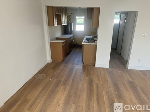 A kitchen area with wooden floors and cabinets.