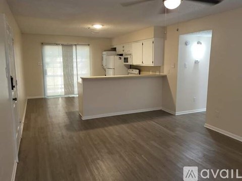 A spacious living area with a kitchenette and hardwood flooring.