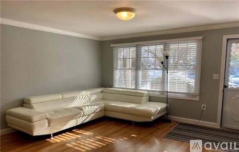 A living room with a white sofa and a window with blinds.