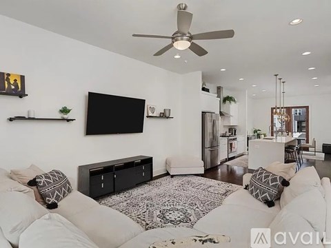 A living room with a white couch and a black television.