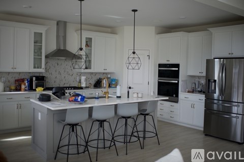 A kitchen with white cabinets and a marble backsplash.