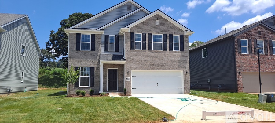 A house with a white garage door and a green hose on the sidewalk.