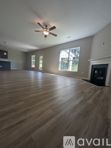 A spacious room with wooden flooring and a ceiling fan.