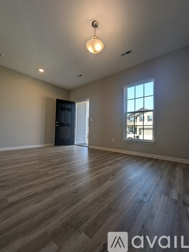 A room with wooden flooring and a window showing a building outside.