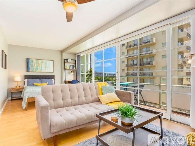 A living room with a large window overlooking a balcony with a couch and a coffee table.