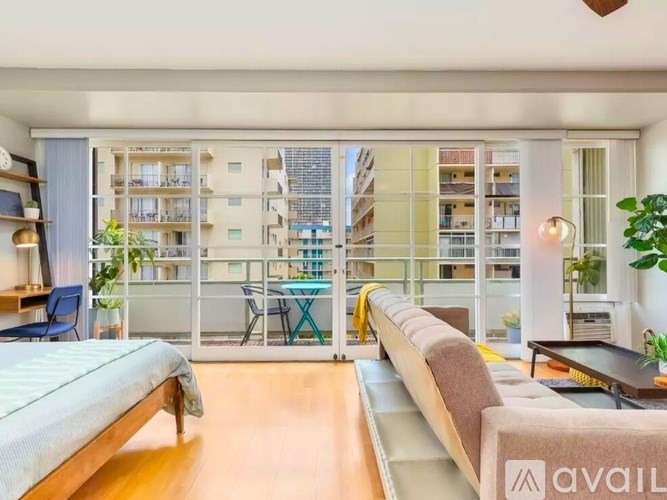 A well-lit, modern living room with a large bed and a balcony overlooking a cityscape.