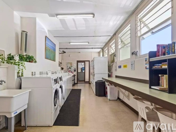 A laundry room with washers and dryers, a sink, and a window.