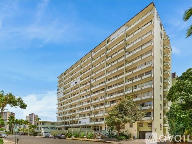 A tall residential building with balconies and a clear sky above.