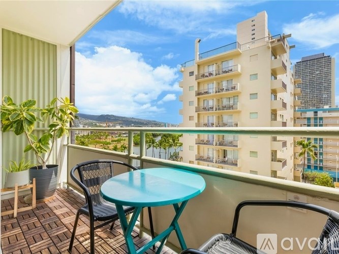 A balcony with a table and chairs overlooking a cityscape.