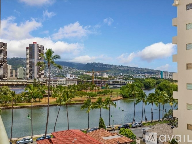 A view from a high-rise building overlooking a waterfront with palm trees and a mountain in the distance.