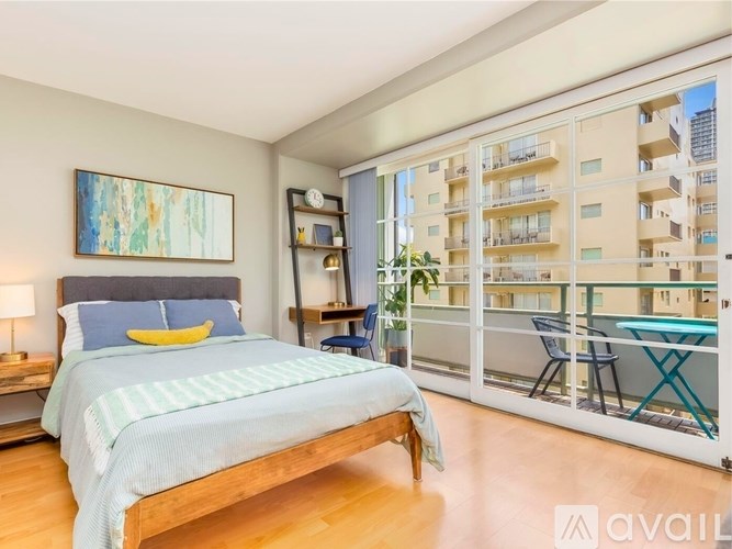 A bedroom with a large bed and a balcony overlooking a building.