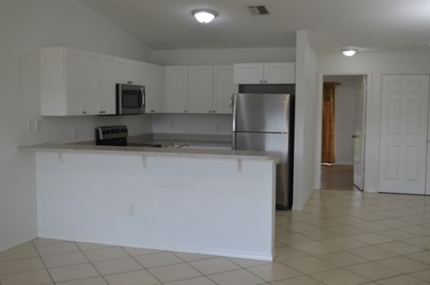 A kitchen with white cabinets and a stainless steel refrigerator.
