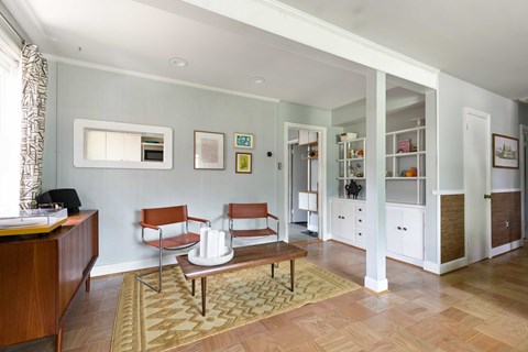 A living room with a brown rug and two chairs.
