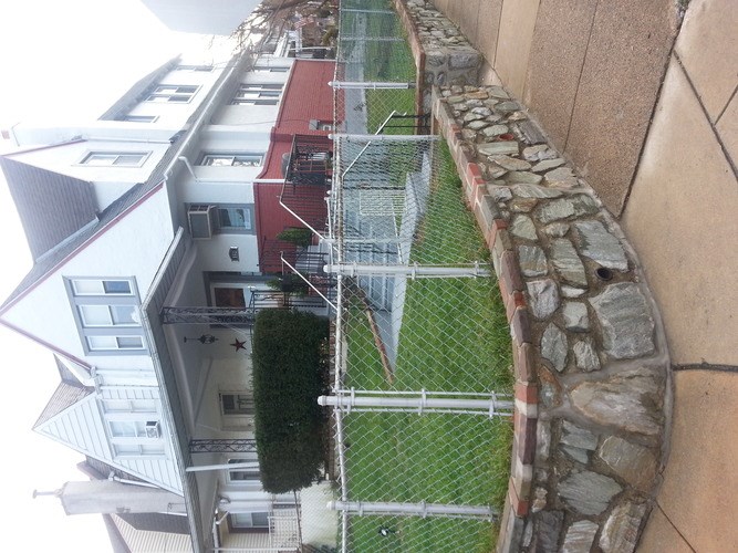 A stone wall borders a green lawn.