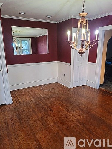 A room with wooden floors and a chandelier hanging from the ceiling.