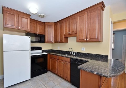 A kitchen with brown cabinets and a white fridge.