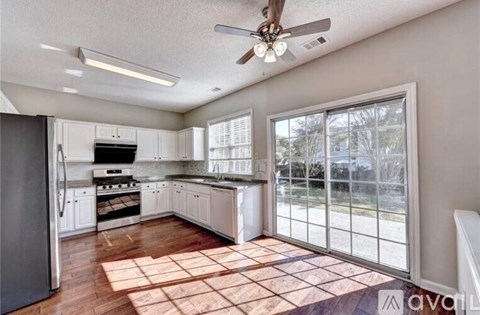 A kitchen with white cabinets and a black fridge.