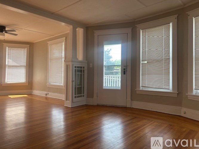 A room with wooden floors and a large window with blinds.