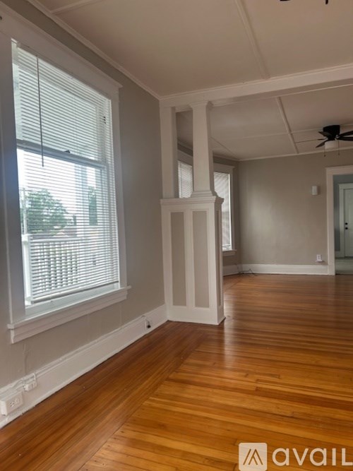 A room with wooden floors and a window with blinds.