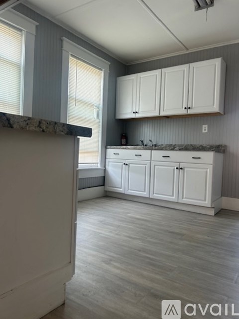 A kitchen with white cabinets and a marble countertop.