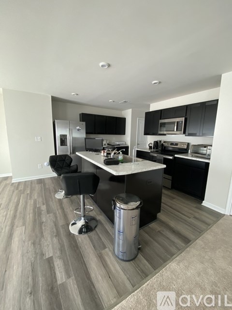 A modern kitchen with a bar stool and a trash bin.