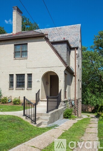 A house with a brick facade and a black metal railing on the front porch.