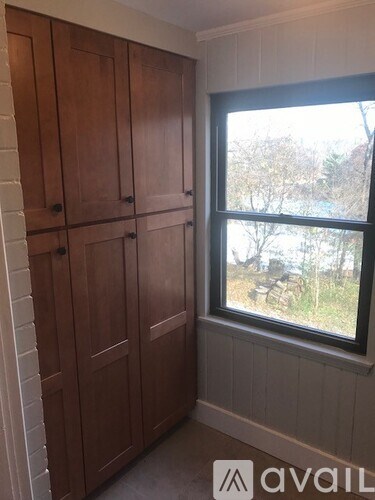 A room with a window and a wooden cabinet.
