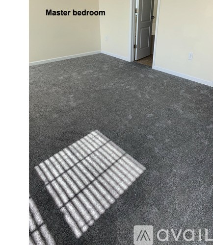 A master bedroom with a carpeted floor and a door.
