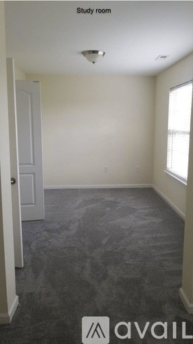 A study room with a carpeted floor and a window.