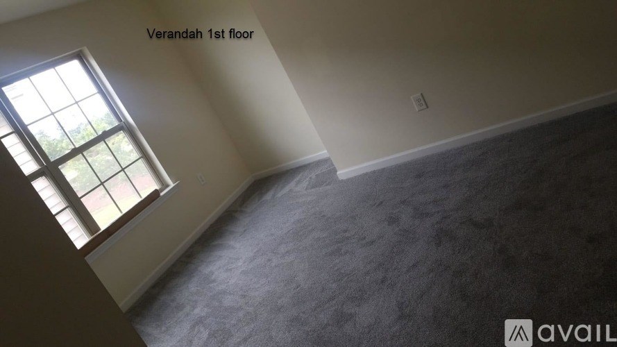 A room with a window on the wall and carpet on the floor.