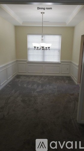 A dining room with a carpeted floor and a chandelier.