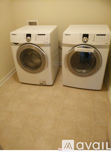 Two white front loading washing machines in a laundry room.