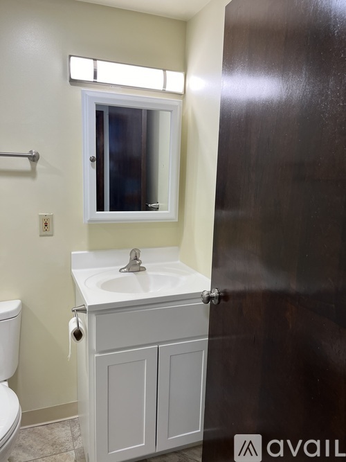 A bathroom with a toilet, sink and mirror.