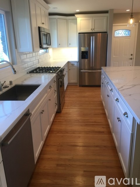 A kitchen with white cabinets and a stainless steel refrigerator.