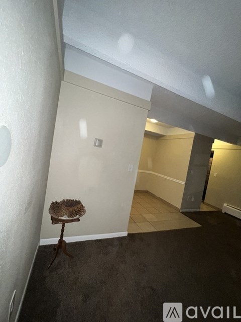 A room with a carpeted floor and a small table with a flower on it.