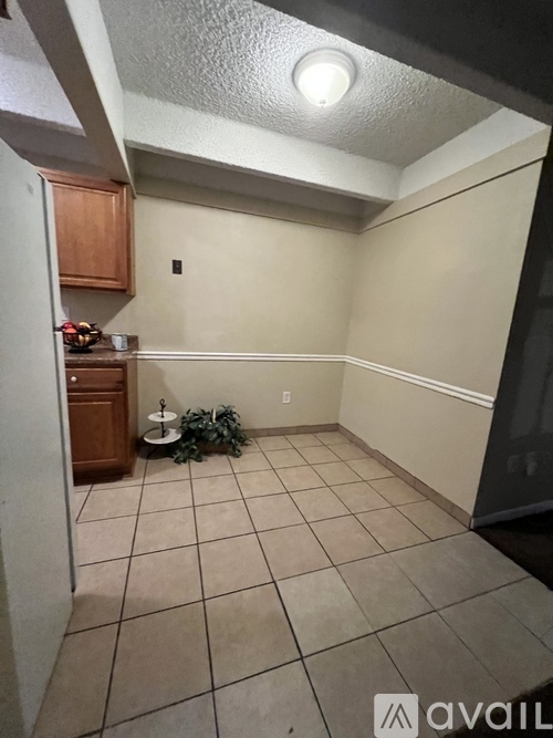 A kitchen area with a tile floor and a small table with a plant on it.