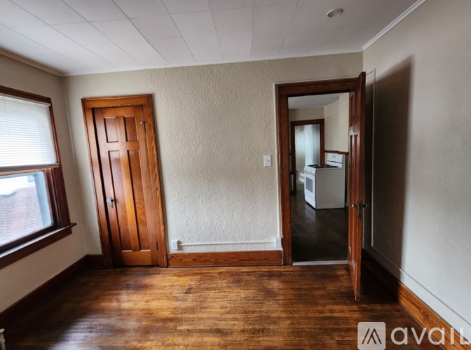 A room with a wooden floor and a door leading to another room.