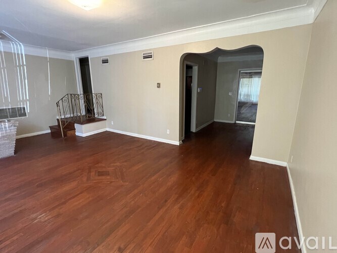 A room with wooden flooring and a balcony with a railing.