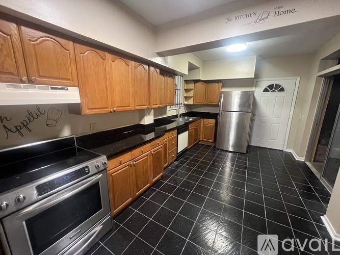A kitchen with wooden cabinets and black tiled flooring.