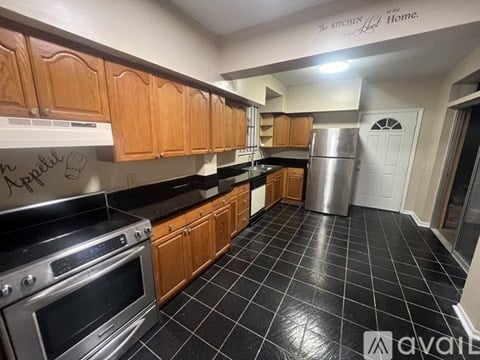 A kitchen with wooden cabinets and black tiled flooring.