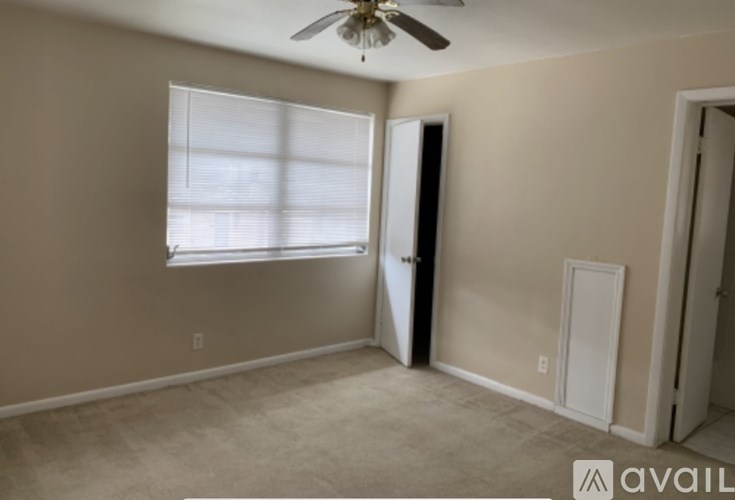 A room with a ceiling fan and a window with blinds.