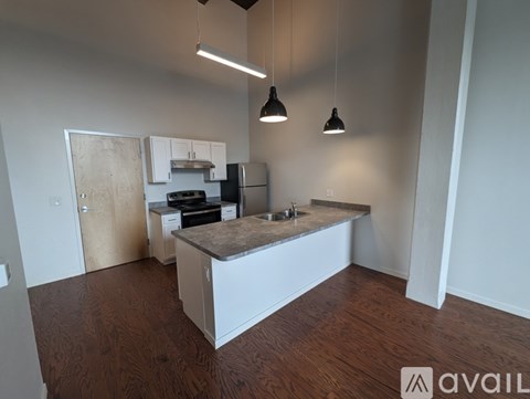 A kitchen with a wooden floor and white cabinets is available for rent.