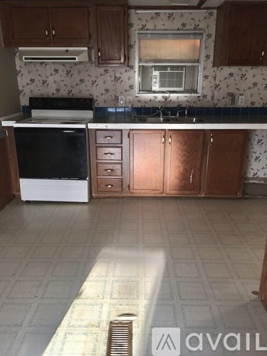 A kitchen with a black oven and brown cabinets.