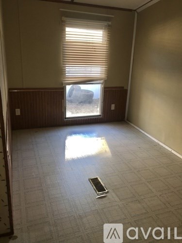 A room with a window and a phone on the floor.