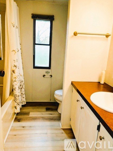 A bathroom with a toilet, sink, and a window.