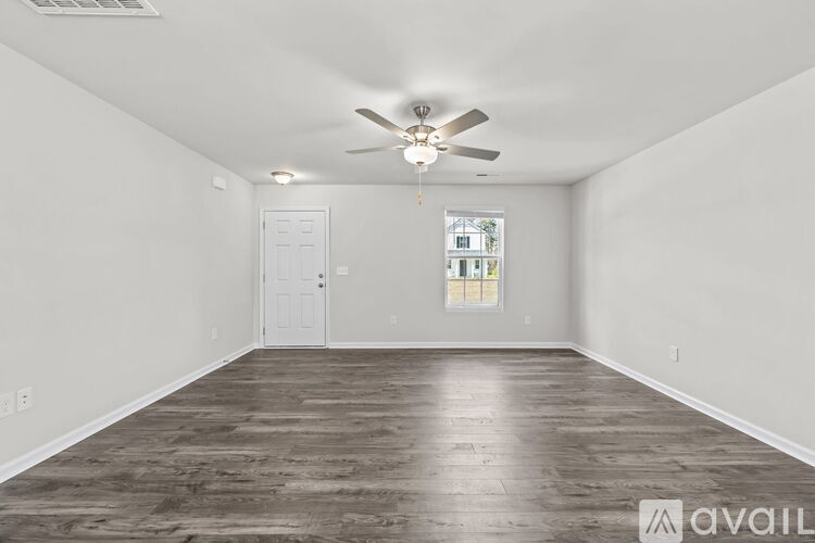 A spacious room with a ceiling fan and wooden flooring.