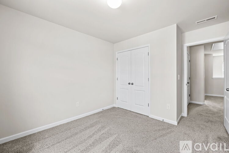 A bedroom with a white door and carpeted floor.