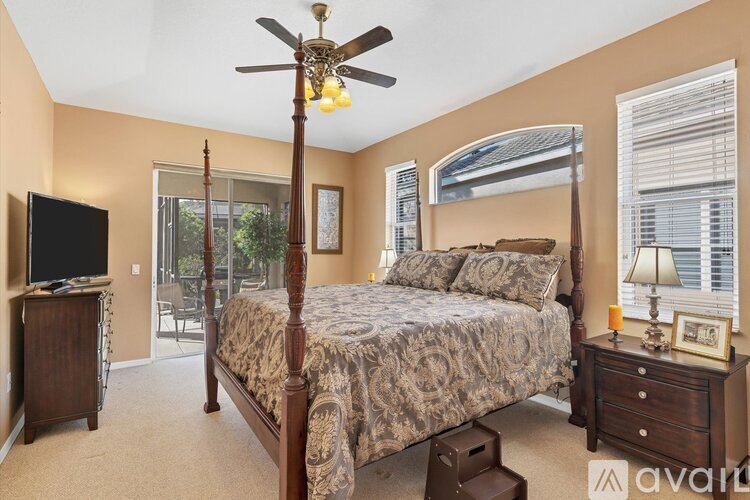 A bedroom with a large bed, a ceiling fan, and a television.